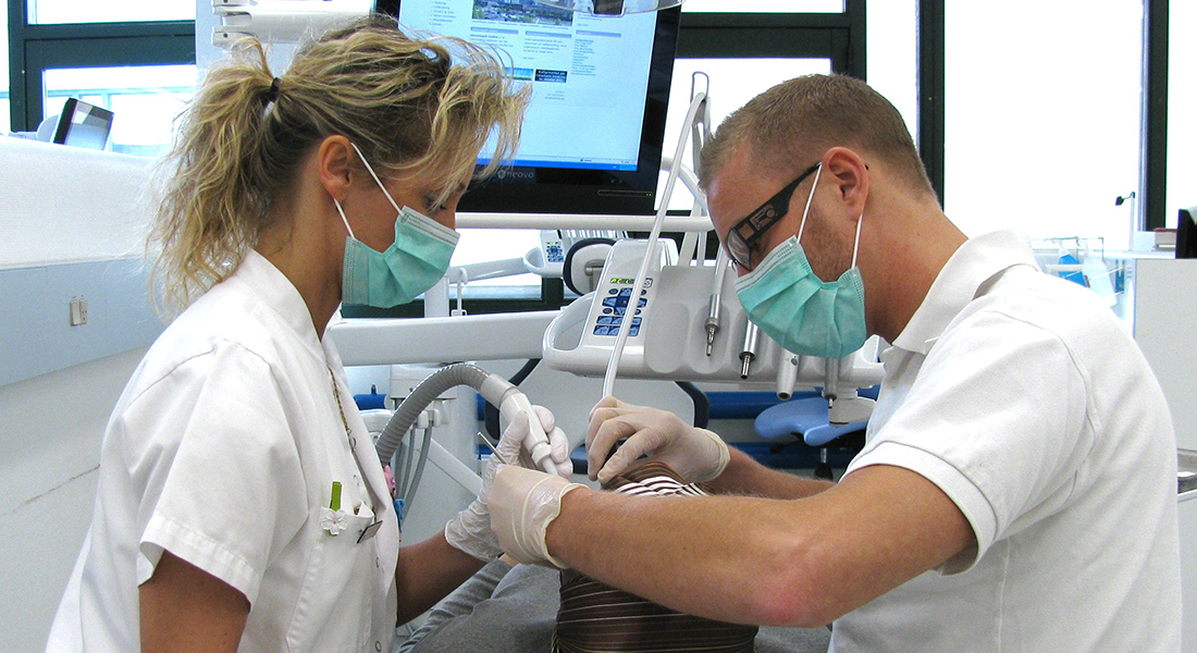 Tandlæge og klinikassistent med en patient i stolen
